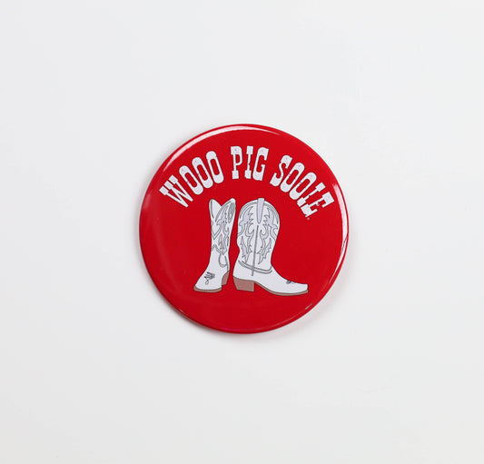 Red button with white cowboy boots and 'Woof Pig Sooie' text on a light gray background, gameday buttons near me, razorback stores in Fayetteville arkansas, clothe boutique