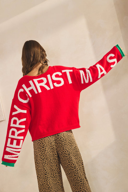 Person wearing a red 'Merry Christmas' sweater with leopard pants, women’s christmas sweater, classy christmas sweaters, red christmas sweater