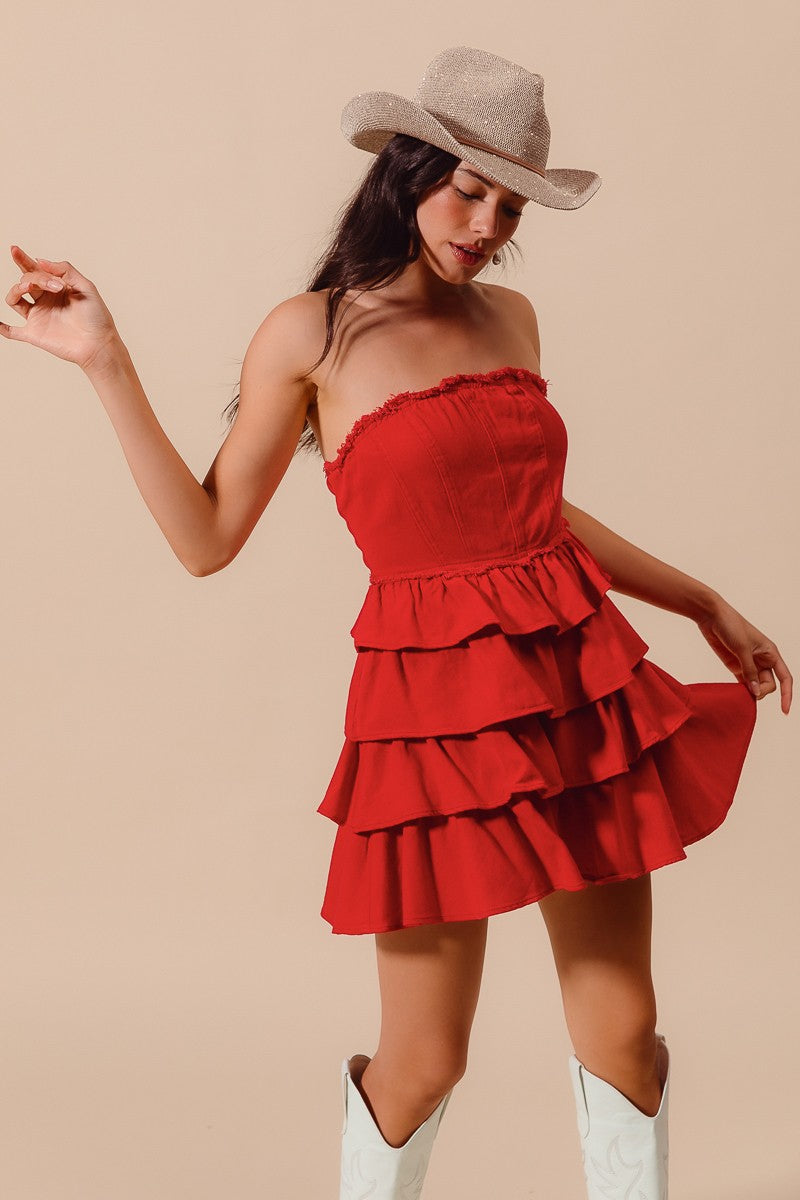 A model wearing a red strapless denim dress with tiered ruffles, paired with white boots and a brown cowboy hat, red strapless dress, red denim dress, red gameday dress, red dress, clothing stores Fayetteville ar