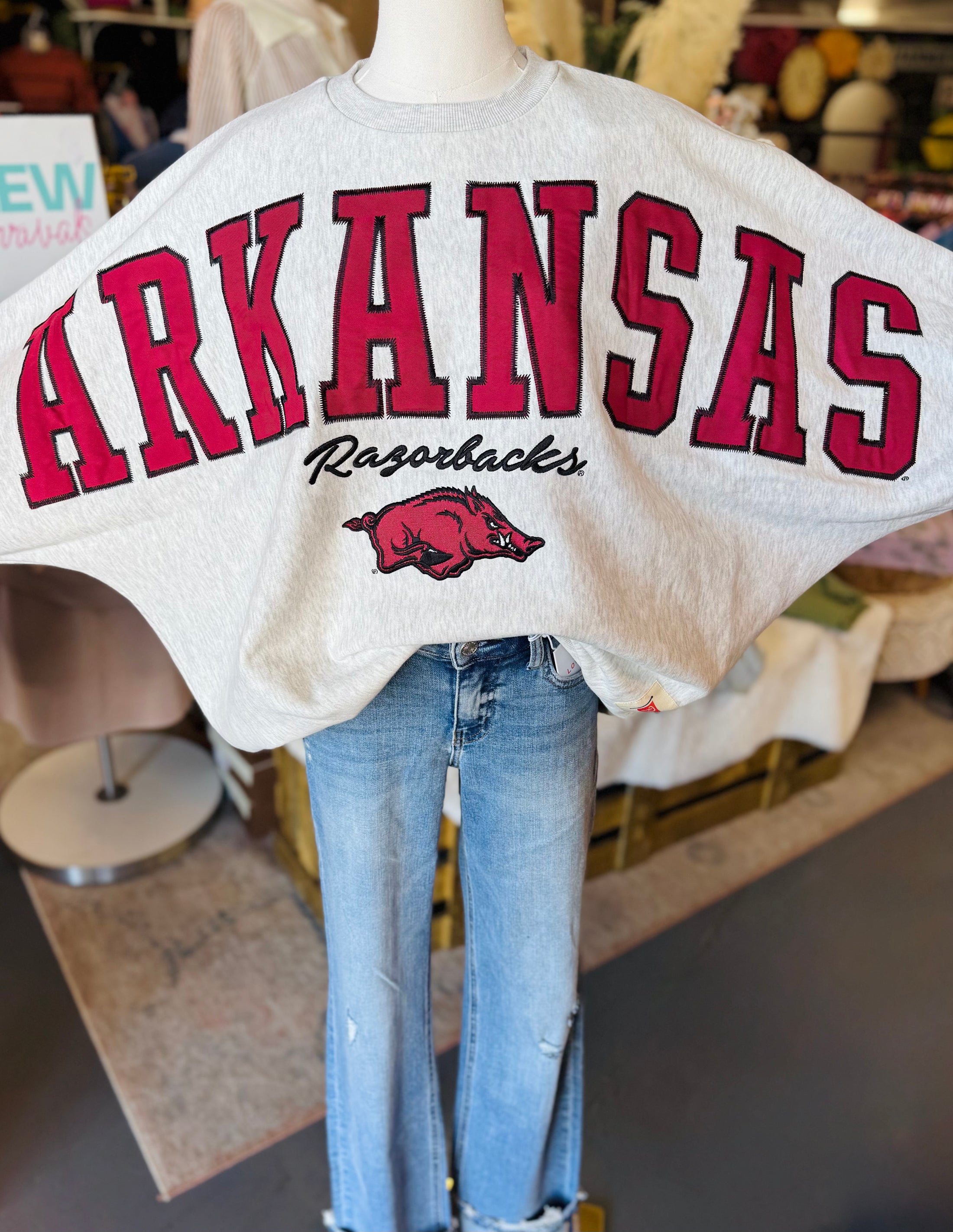 Mannequin wearing a 'ARKANSAS Razorbacks' sweatshirt with jeans in a Fayetteville ar store for Razorback boutique clothing, riff raff boutique razorback clothing, shopping near me Fayetteville ar Fayetteville mall, arkansas razorback store, store near me, Fayetteville ar stores, arkansas razorback store