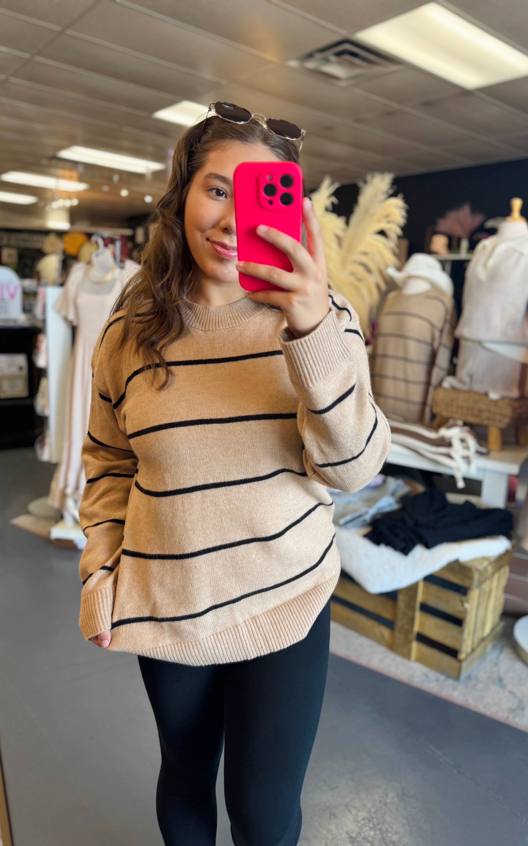 Person wearing a beige and black striped sweater in a clothing store Fayetteville ar Whimsy Whoo boutique and shoe store, boutiques near me, sweaters for women