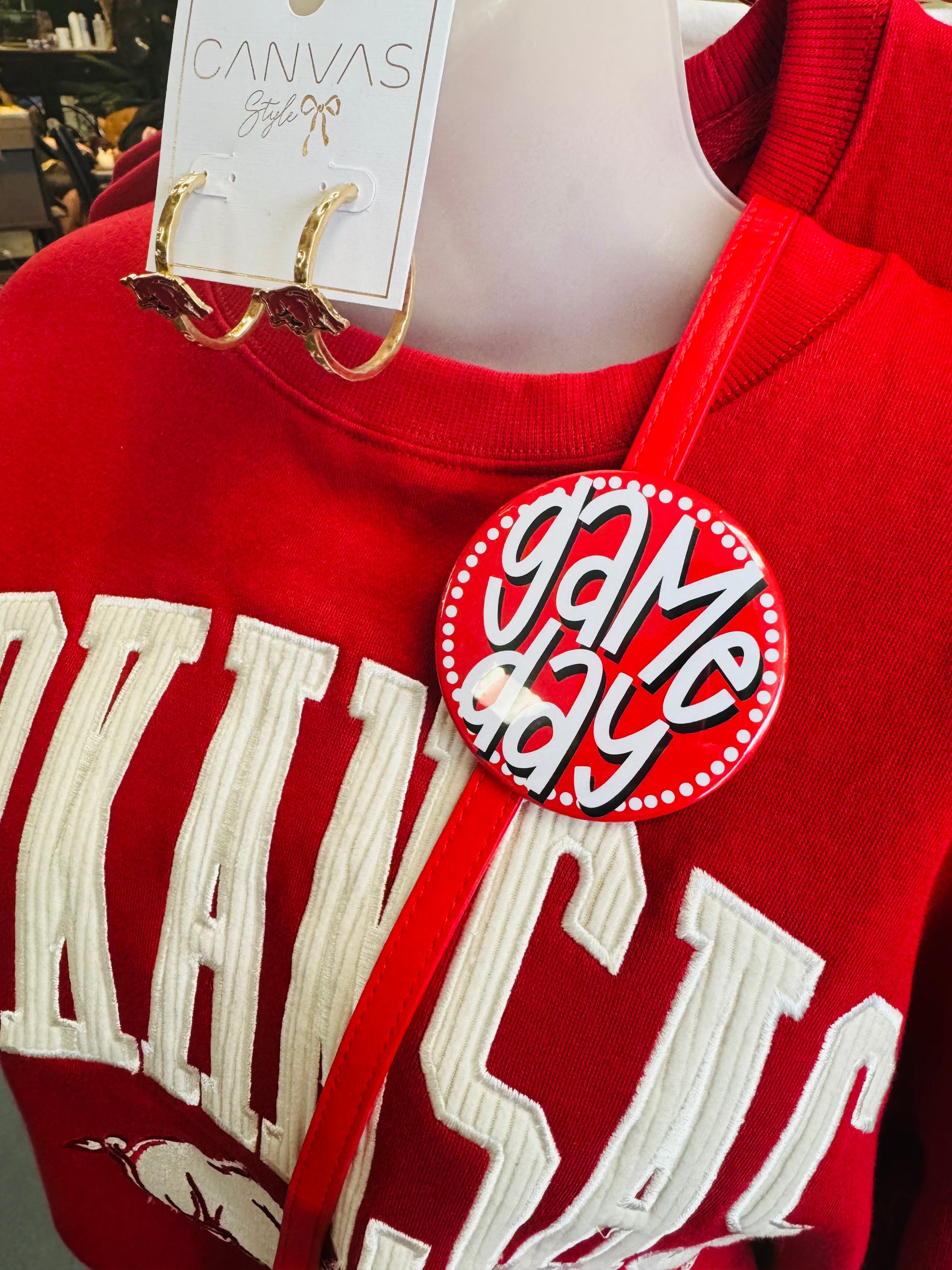 Red sweatshirt with white text and a 'Game Day' pin, displayed on a mannequin.