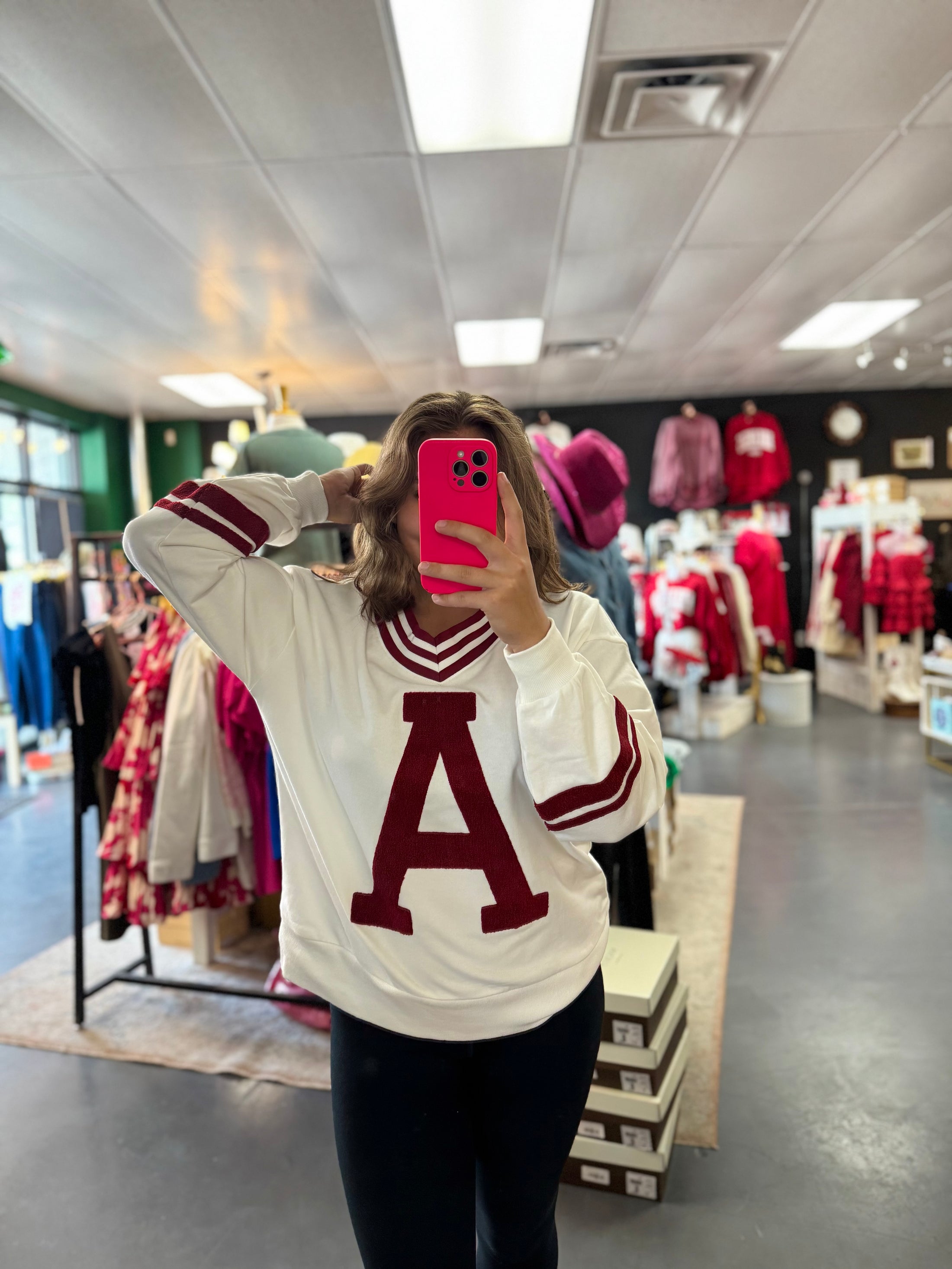 Person wearing a white sweater with a red 'A' in a store setting, Arkansas sweatshirt, arkansas sweatshirt women, arkansas sweatshirt vintage, arkansas sweatshirt near me, arkansas sweatshirt nearby, razorback shoppe