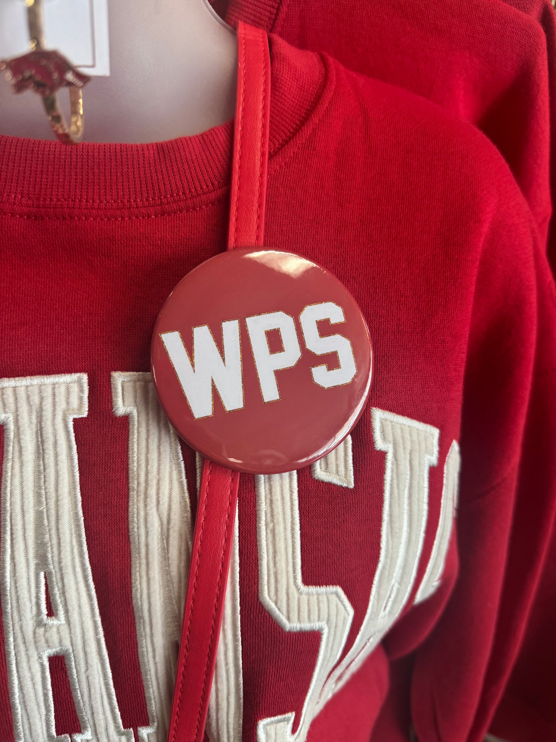 Red sweatshirt with a 'WPS' button on a mannequin, college game day pins, razorback gameday pins, Arkansas gameday pins, razorback store online
