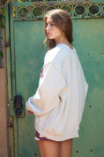 Load image into Gallery viewer, women’s Arkansas razorback sweatshirt with an oversized fit paired with denim shorts for a casual Arkansas game day outfit.
