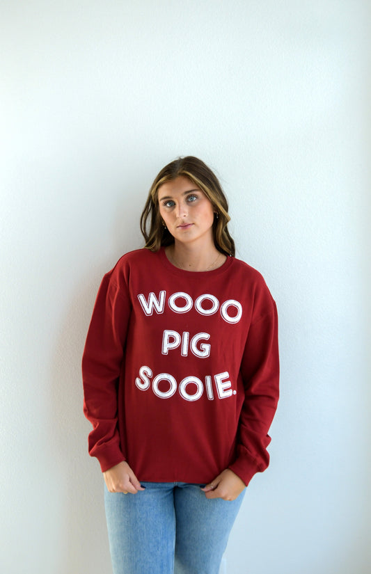 Person wearing a red sweatshirt with 'WOO PIG SOOIE' text in a Fayetteville ar boutique store, Arkansas razorback store, shopping Fayetteville, razorback sweatshirt, arkansas razorback sweatshirt for women