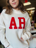 Load image into Gallery viewer, Close-up of the high-quality red AR embroidery on the cream mock neck sweatshirt, exclusive to Whimsy Store’s Razorback football store collection.
