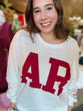 Load image into Gallery viewer, Woman wearing the trendy white Arkansas crewneck sweatshirt with bold red lettering, a gameday favorite for repping the Hogs at Whimsy Whoo. AR reversible sweatshirt
