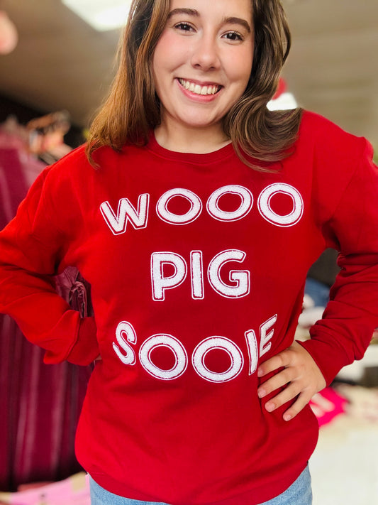 A woman in the vibrant red Wooo Pig Sooie Razorback sweatshirt, showcasing the high-quality chenille lettering for Arkansas gameday fans at Whimsy Whoo boutique store in FAyetteville, AR.