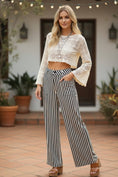 Load image into Gallery viewer, The back view of the black and white vertical striped pants, showcasing the elongating silhouette and comfortable high-rise waist.
