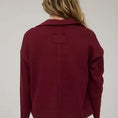 Load image into Gallery viewer, The back view of the burgundy textured knit polo showing the vertical exposed seam detailing. Shop this unique style at Whimsy Boutique, the best boutique near me for high-quality spring fashion.
