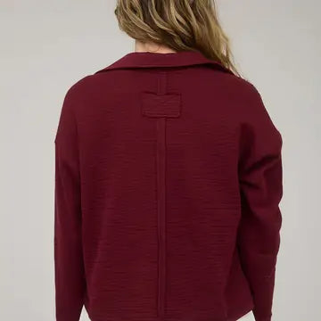 The back view of the burgundy textured knit polo showing the vertical exposed seam detailing. Shop this unique style at Whimsy Boutique, the best boutique near me for high-quality spring fashion.