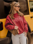 Load image into Gallery viewer, Fashionable gameday style featuring the crimson Arkansas Hogs polka dot sweatshirt leaning against a yellow vehicle.
