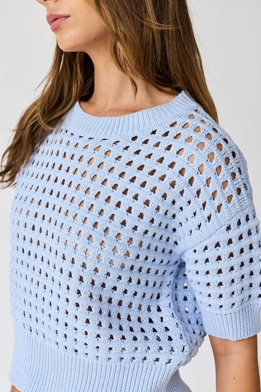 A close-up detail of the intricate open-weave crochet knit and ribbed crew neckline on the Sky Blue Oh Hey Crochet! top