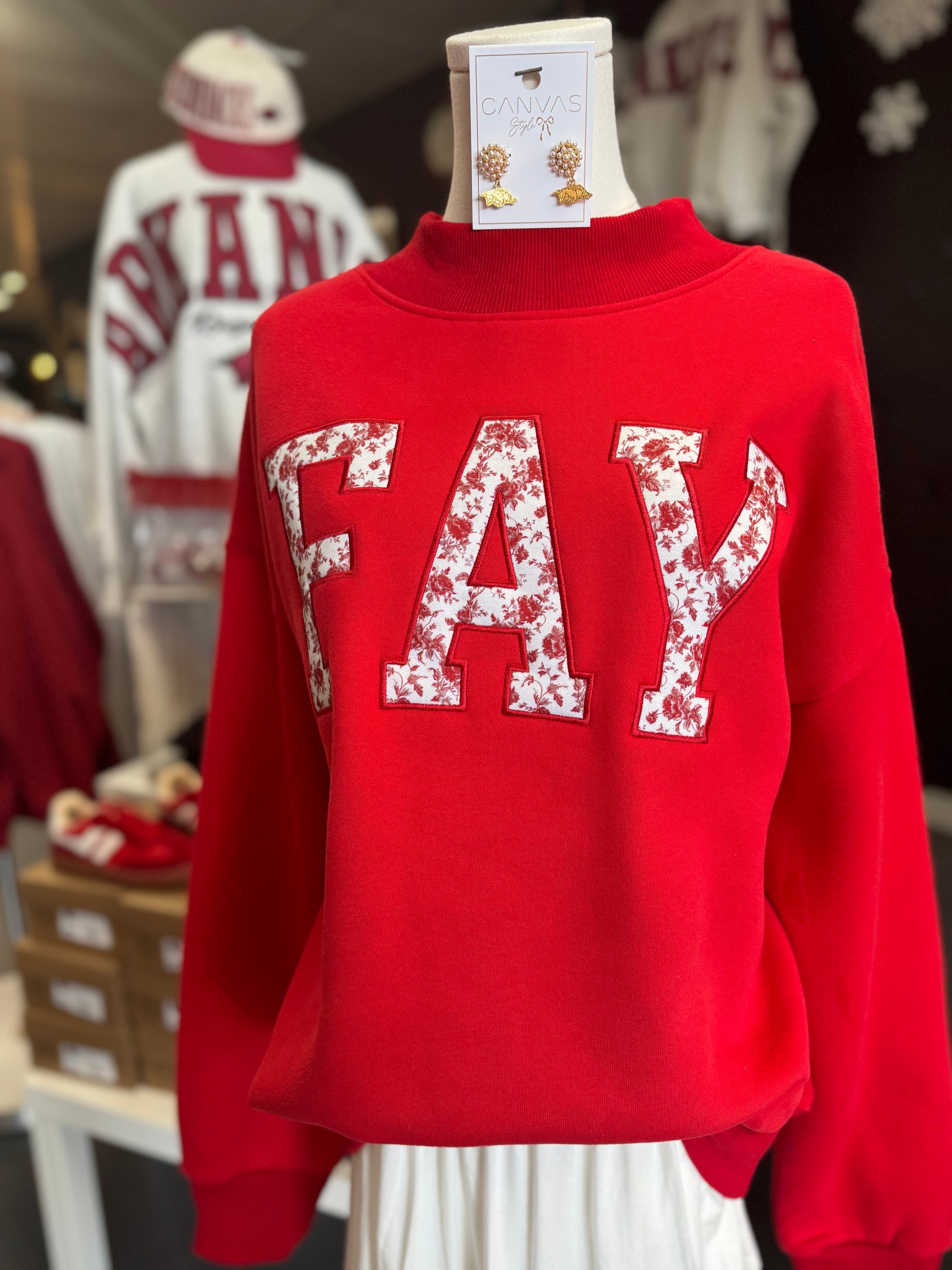 A close-up of the "FAY" lettering and vintage-inspired rose detail on the red Arkansas mock neck sweatshirt at Whimsy Whoo Boutique.