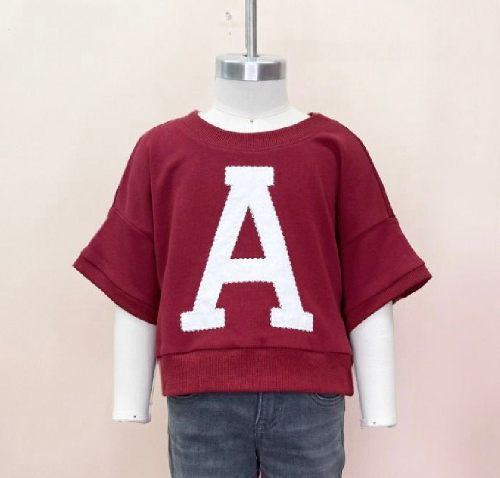 A child's oversized maroon sweatshirt with the letter 'A' in white stitching on the front.