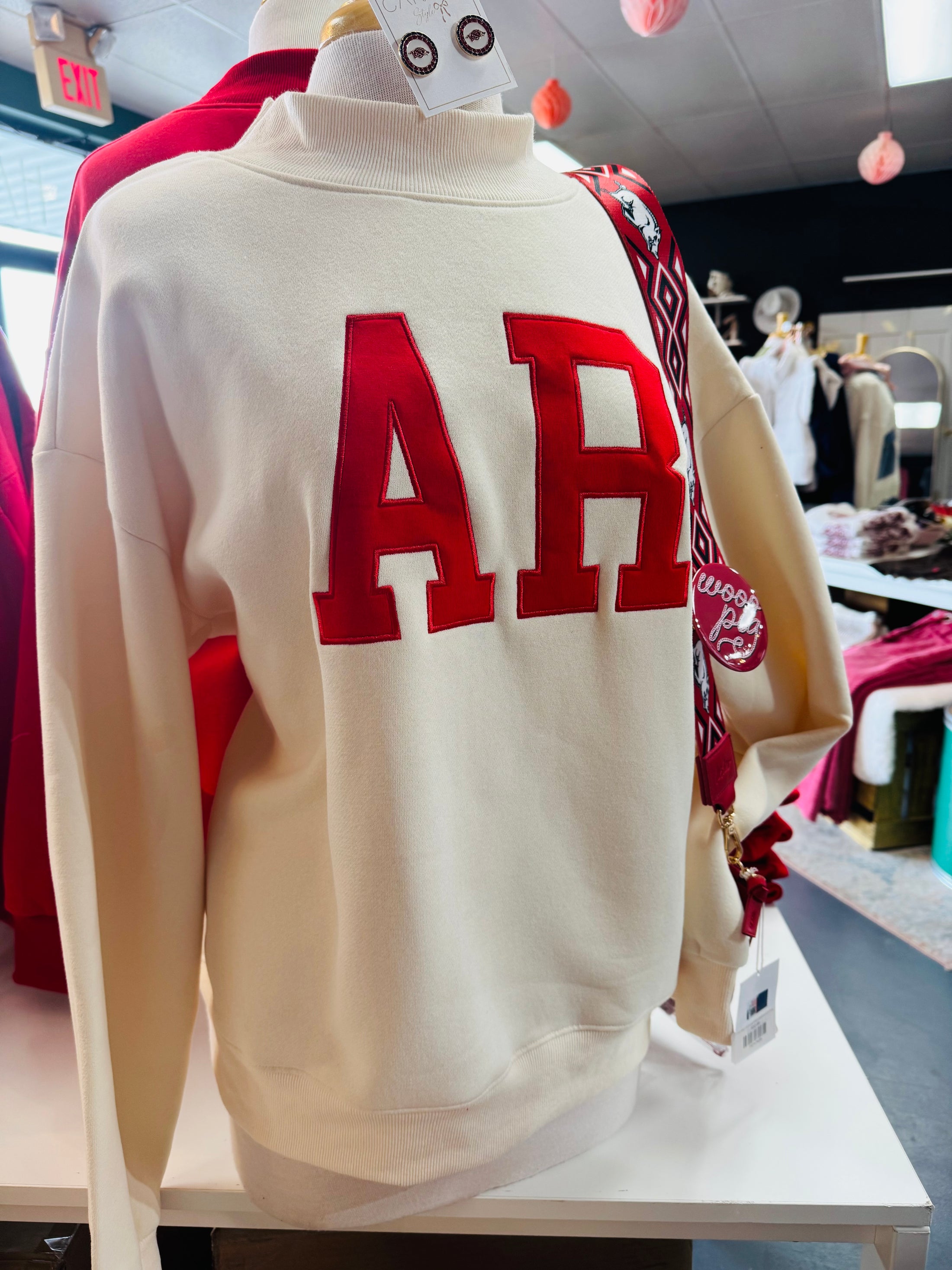 Store display at Whimsy Store featuring the AR mock neck sweatshirt styled with Razorback accessories, positioned as the best clothing store near me for gameday gear.