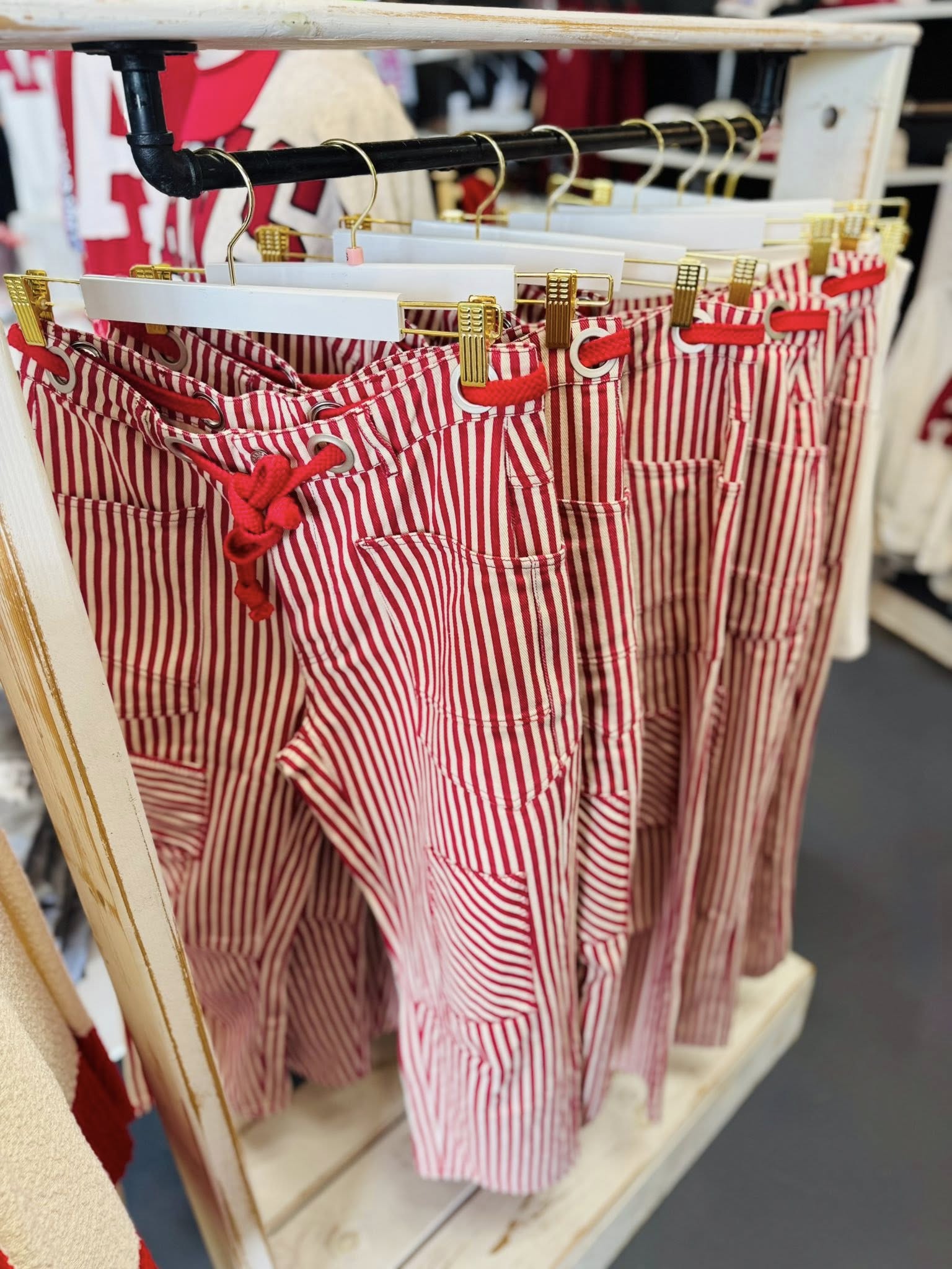 A close-up of red and white striped pull-on barrel pants hanging in a Fayetteville boutique, perfect for an Arkansas Razorback gameday outfit.