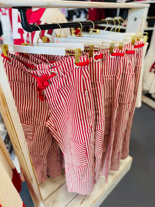 A close-up of red and white striped pull-on barrel pants hanging in a Fayetteville boutique, perfect for an Arkansas Razorback gameday outfit.
