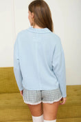Load image into Gallery viewer, Detailed back view of the Spring Blue textured knit polo showing the vertical exposed seam and relaxed collar. Available at Whimsy Boutique, your favorite boutique near me for unique spring essentials.
