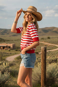 Load image into Gallery viewer, A model wearing the Tailgate Chic Striped Sweater, featuring bold red and white horizontal stripes and puff sleeve details, paired with denim shorts and a tan cowboy hat.
