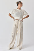 Load image into Gallery viewer, Front view of the Oh Hey Crochet! open-knit cropped sweater in white, styled with wide-leg utility pants at Whimsy Whoo Boutique.
