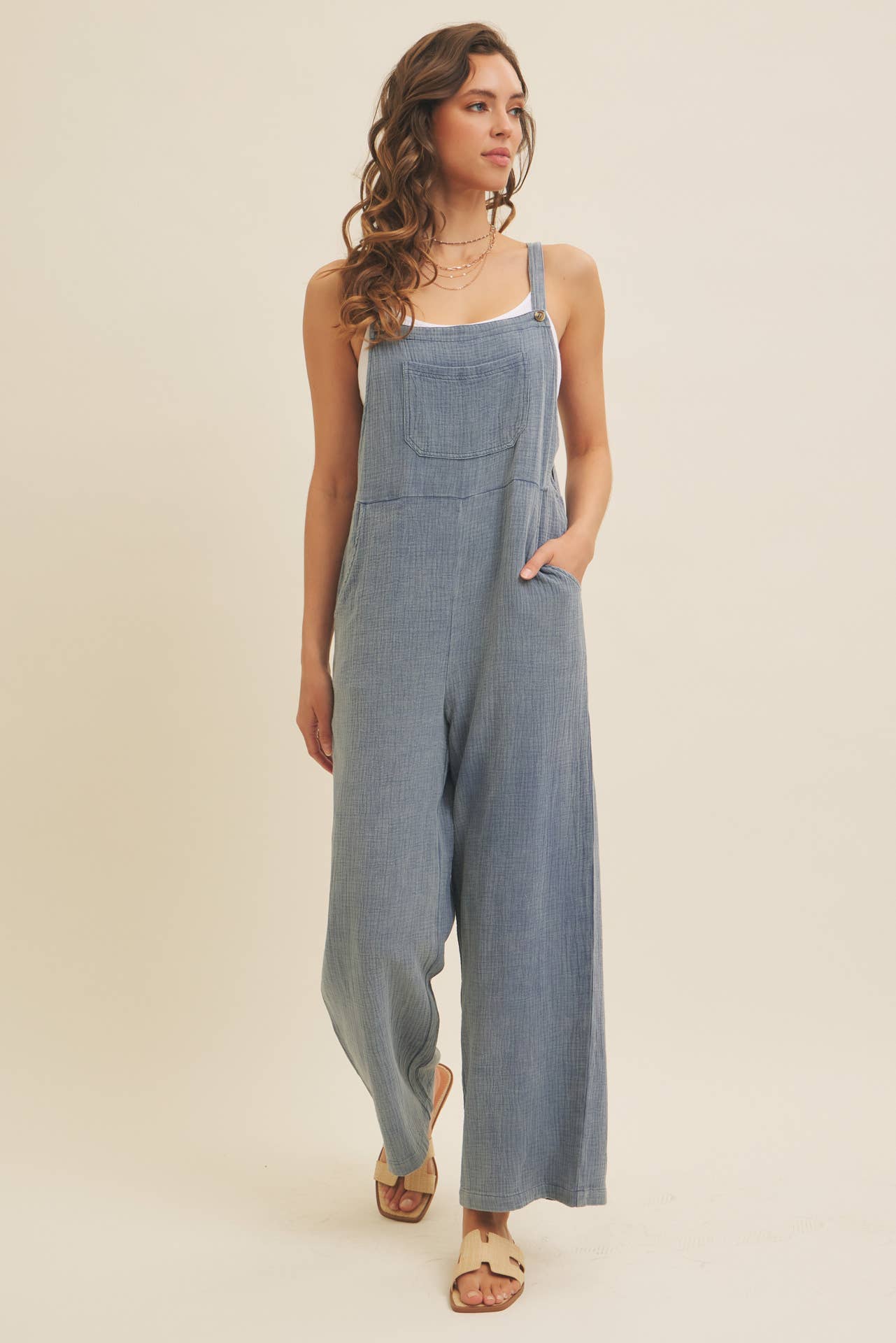 Woman wearing a blue linen-blend jumpsuit on a beige background