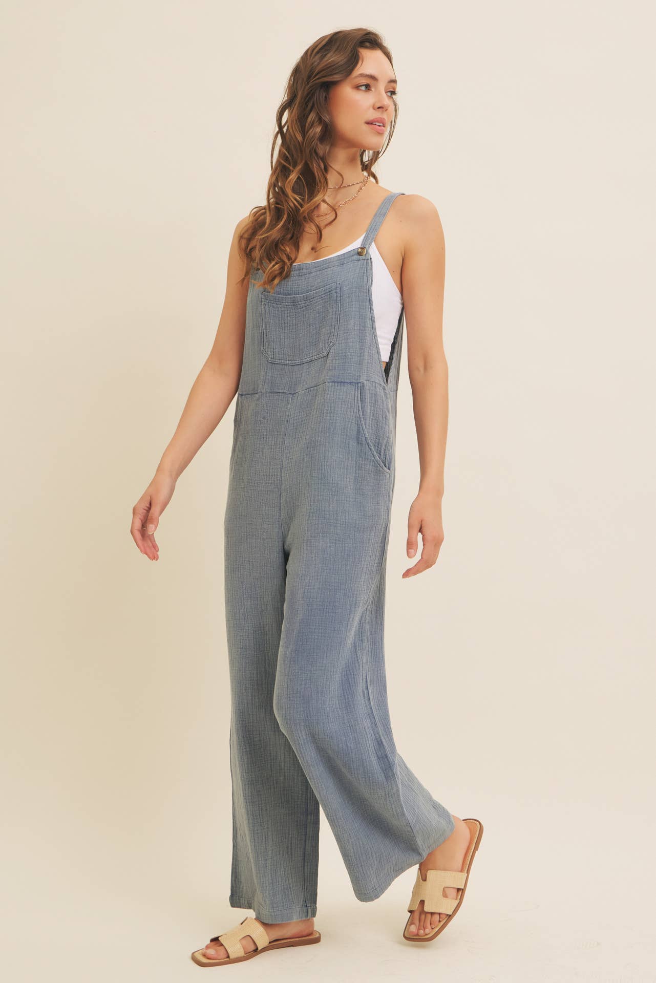 Woman wearing a blue linen-blend jumpsuit on a beige background