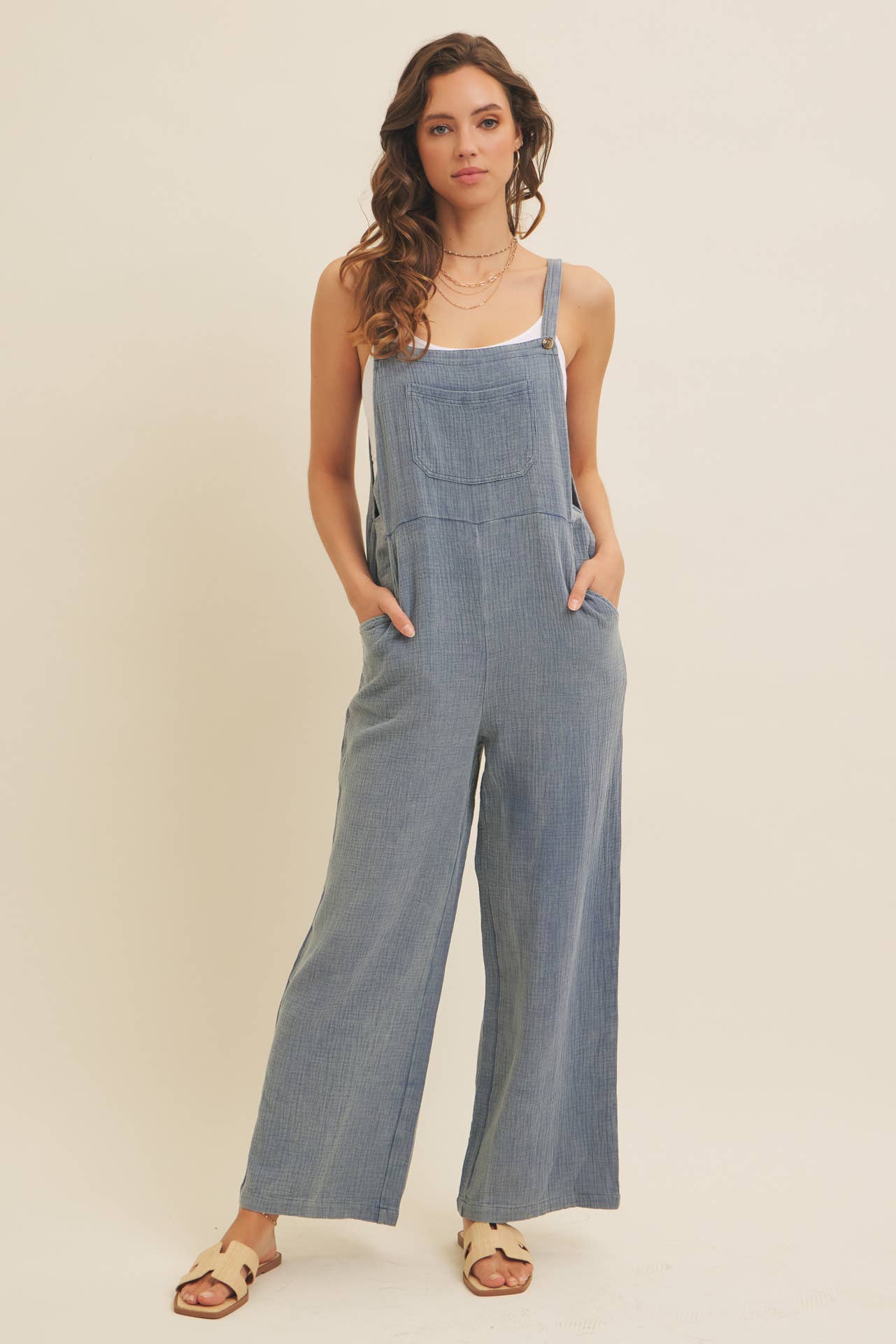 Woman wearing lenin-blend blue overalls against a plain background