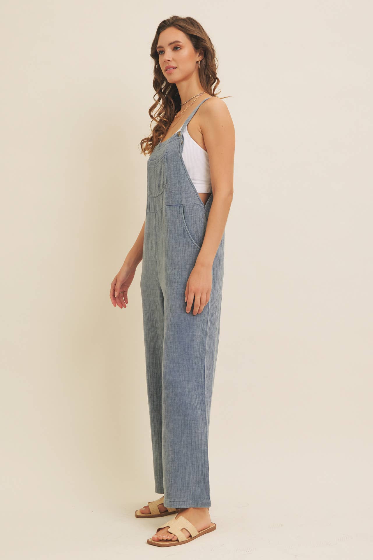 Woman wearing a blue linen-blend jumpsuit on a beige background