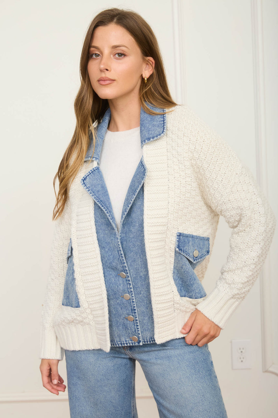 Woman wearing a white cardigan over a denim jacket with a white wall background, Fayetteville arkansas shopping near me