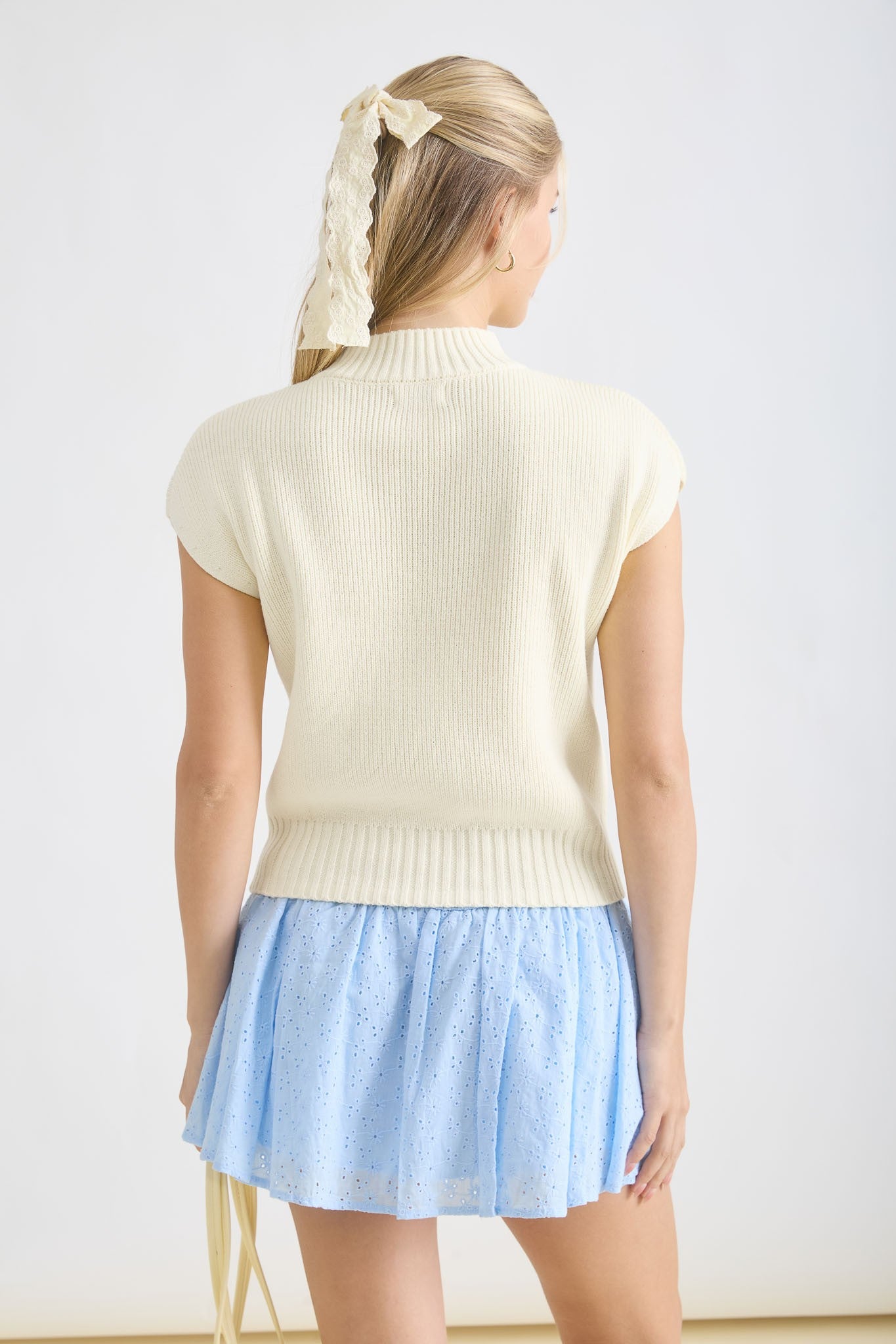 Back view of a women’s sleeveless mock neck pullover in classic cream. Visit our Fayetteville boutique or shop Whimsy Boutique online for the best boutique near me experience
